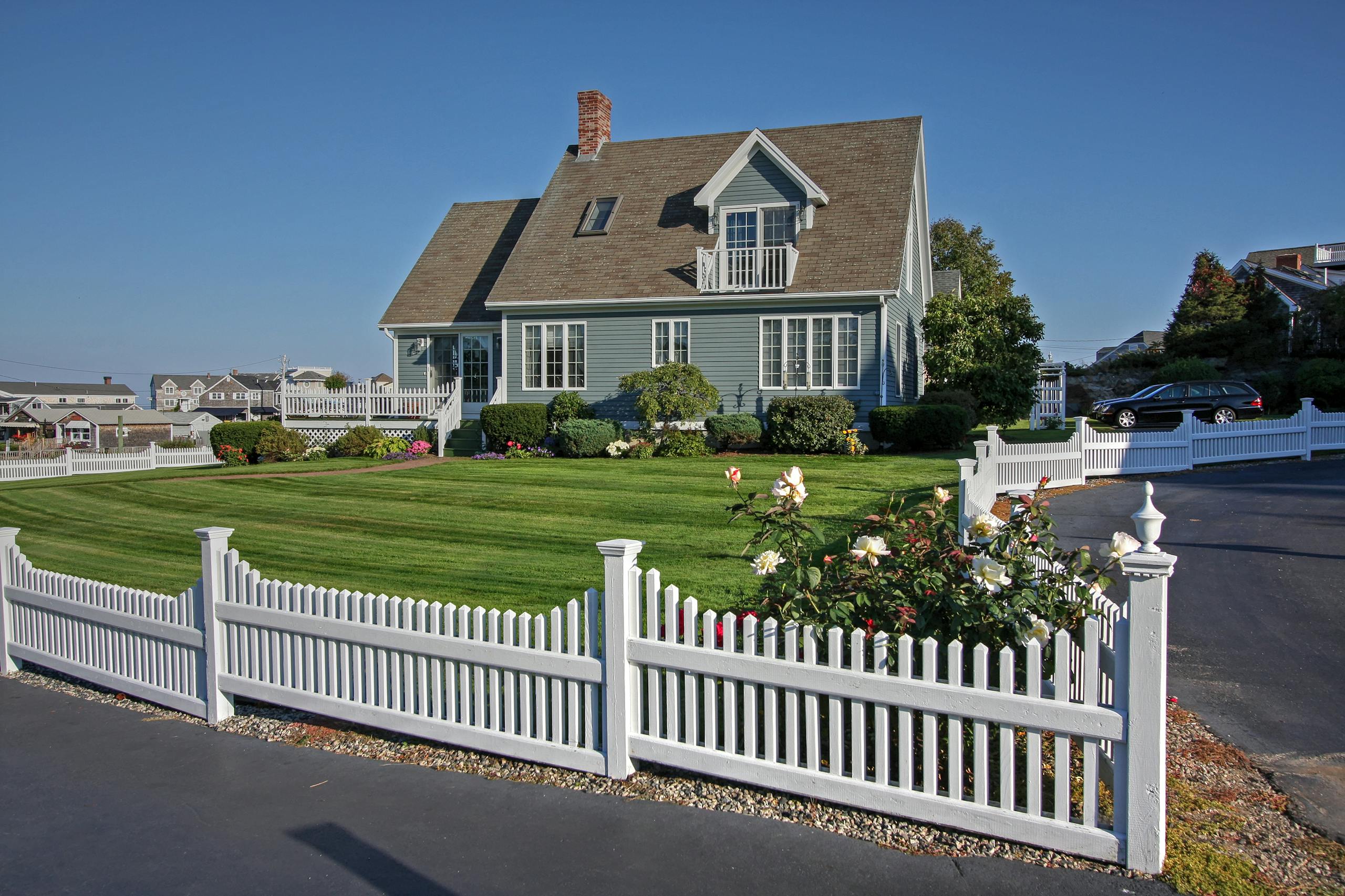 A picturesque New England home with white picket fence and manicured lawn, perfect for residential living.