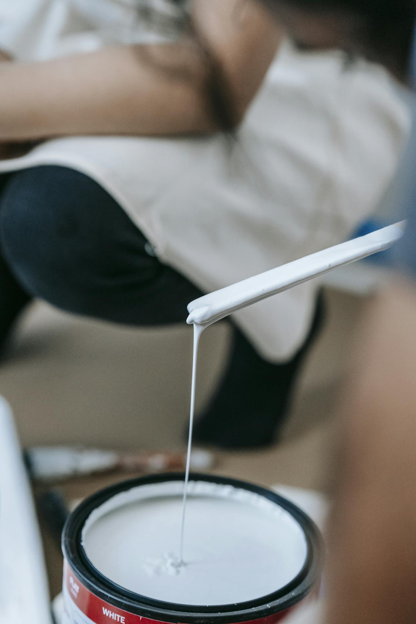 Close-up of a woman mixing white paint, ready to apply in a home renovation project.